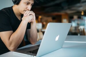 jovem com notebook refletindo sobre fé e inteligência artificial