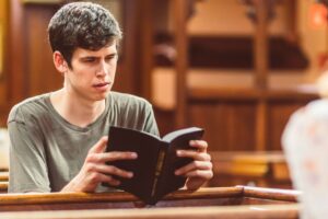 Adolescente lendo a Bíblia em banco de igreja, representando liberdade e fé cristã