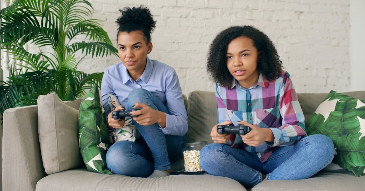 adolescente disperso jogando videogame com o celular ao lado