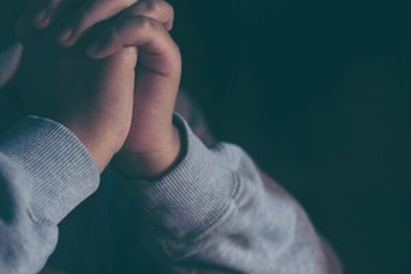 Adolescente em oração com as mãos unidas, simbolizando o pedido específico que a história da menina daltônica curada ensina ao líder de adolescentes.