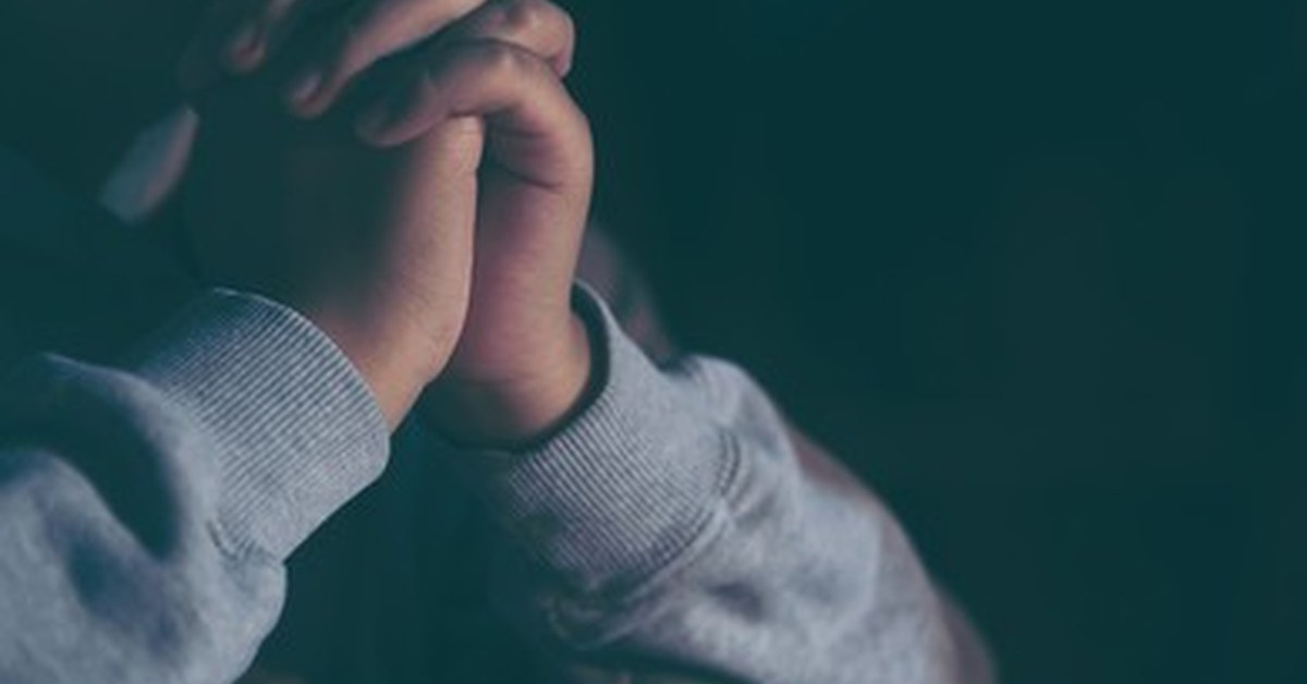 Adolescente em oração com as mãos unidas, simbolizando o pedido específico que a história da menina daltônica curada ensina ao líder de adolescentes.